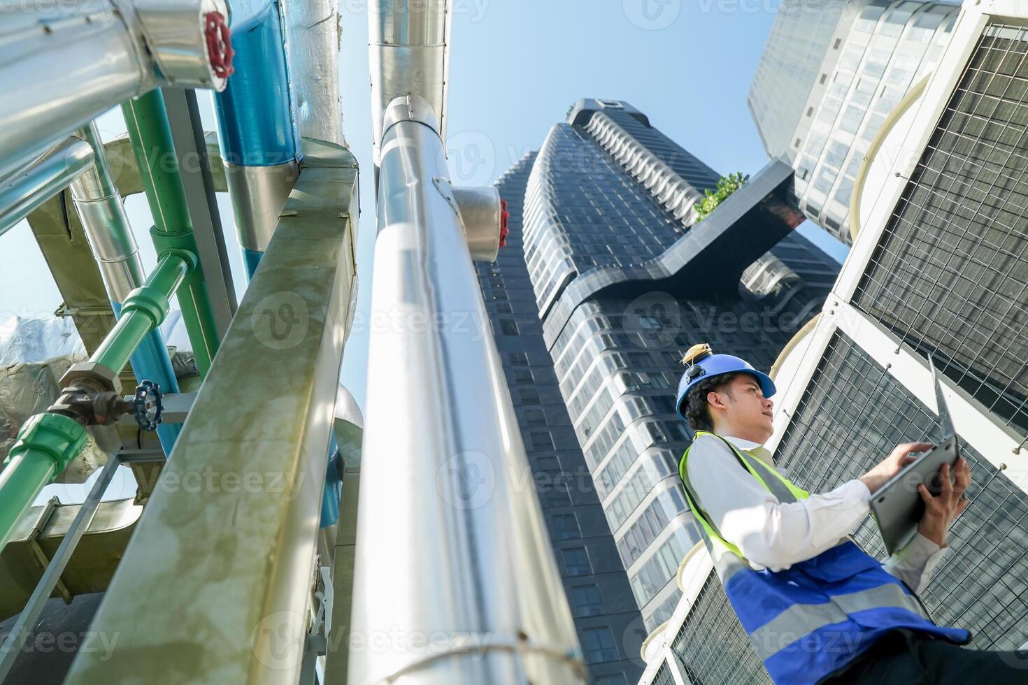 Industrial engineer adjusting pipeline valve with radio communication on construction site. Engineer on urban construction site using radio to coordinate with team on a sunny industrial rooftop. photo
