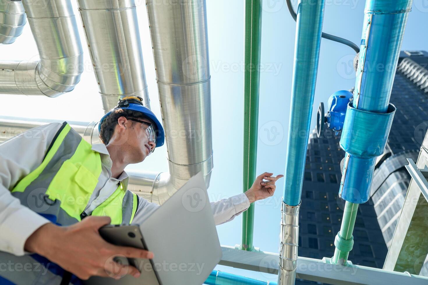 Industrial engineer adjusting pipeline valve with radio communication on construction site. Engineer on urban construction site using radio to coordinate with team on a sunny industrial rooftop. photo