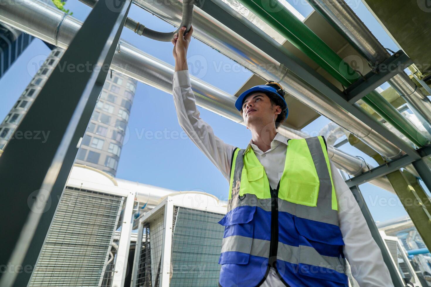 Industrial engineer adjusting pipeline valve with radio communication on construction site. Engineer on urban construction site using radio to coordinate with team on a sunny industrial rooftop. photo