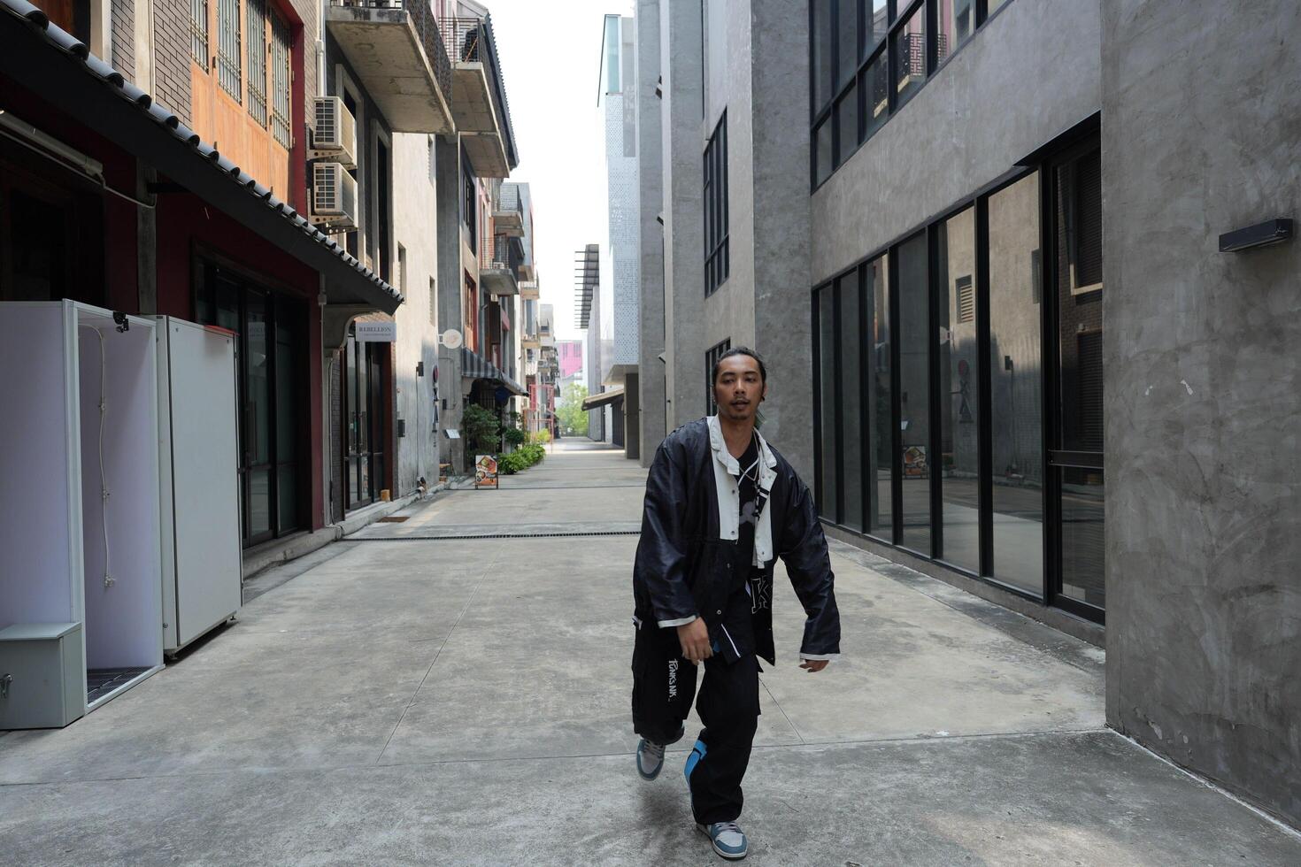 ASian man is dancing in hip hop style at outdoor space. Professional solo dancer is performing in public area. photo