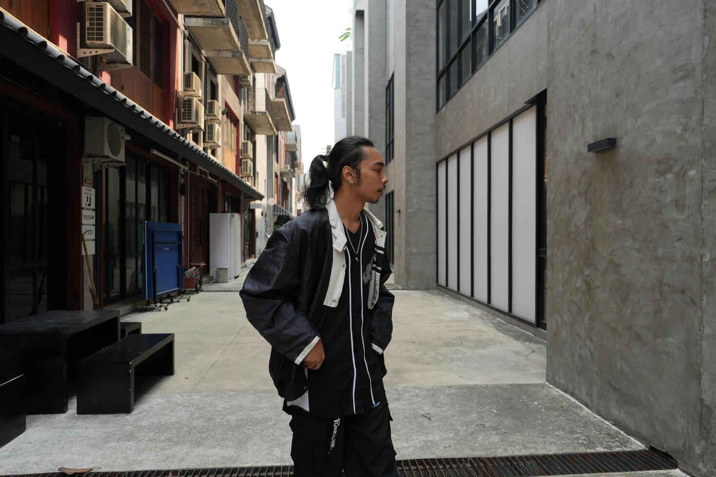 ASian man is dancing in hip hop style at outdoor space. Professional solo dancer is performing in public area. photo