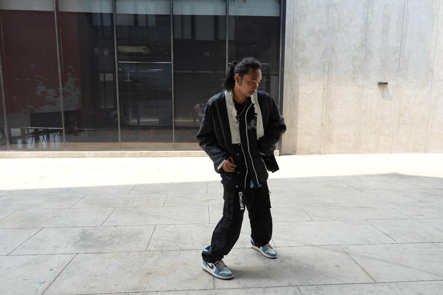 ASian man is dancing in hip hop style at outdoor space. Professional solo dancer is performing in public area. photo
