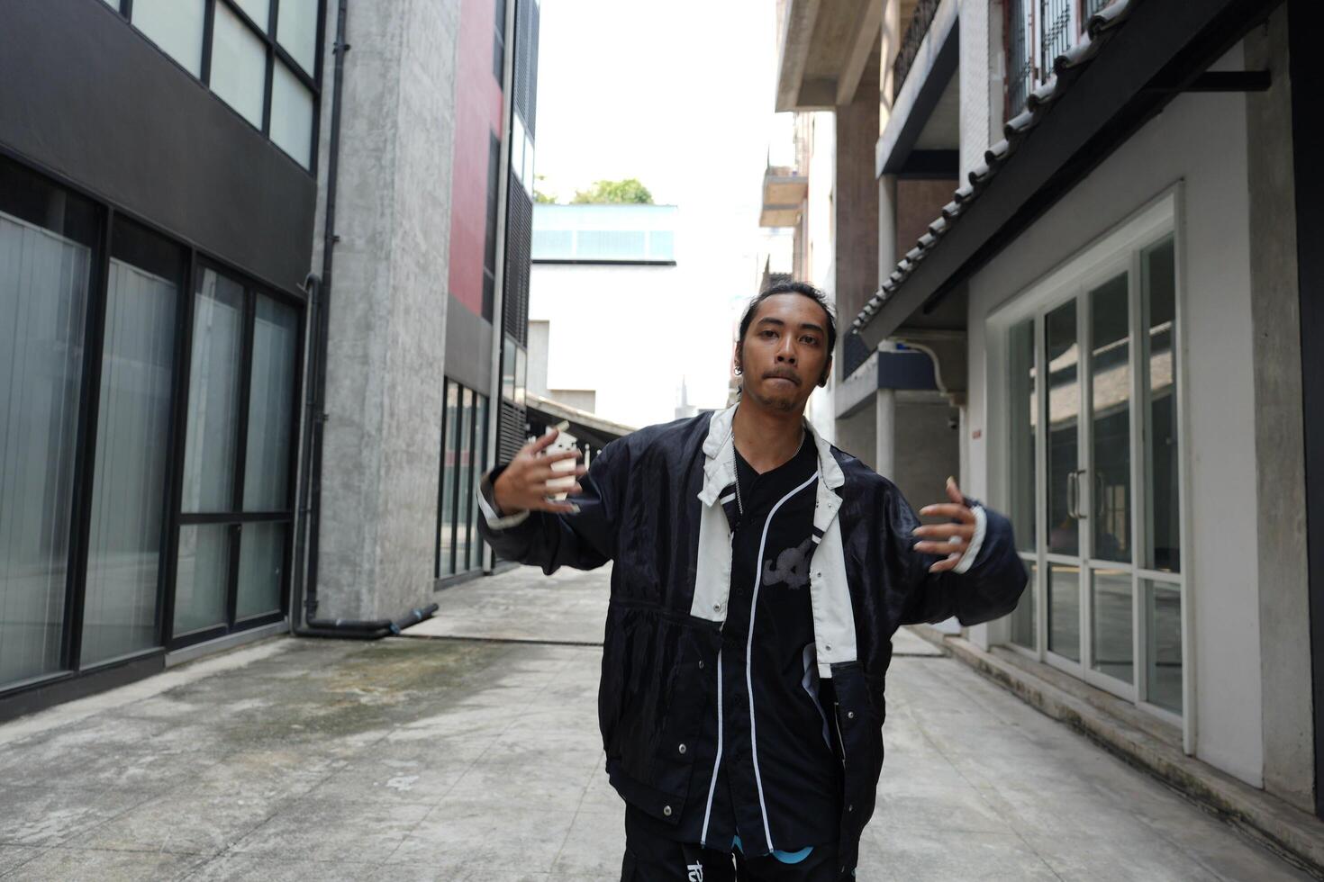 ASian man is dancing in hip hop style at outdoor space. Professional solo dancer is performing in public area. photo