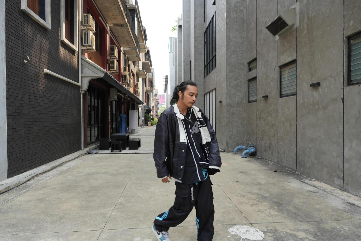 ASian man is dancing in hip hop style at outdoor space. Professional solo dancer is performing in public area. photo