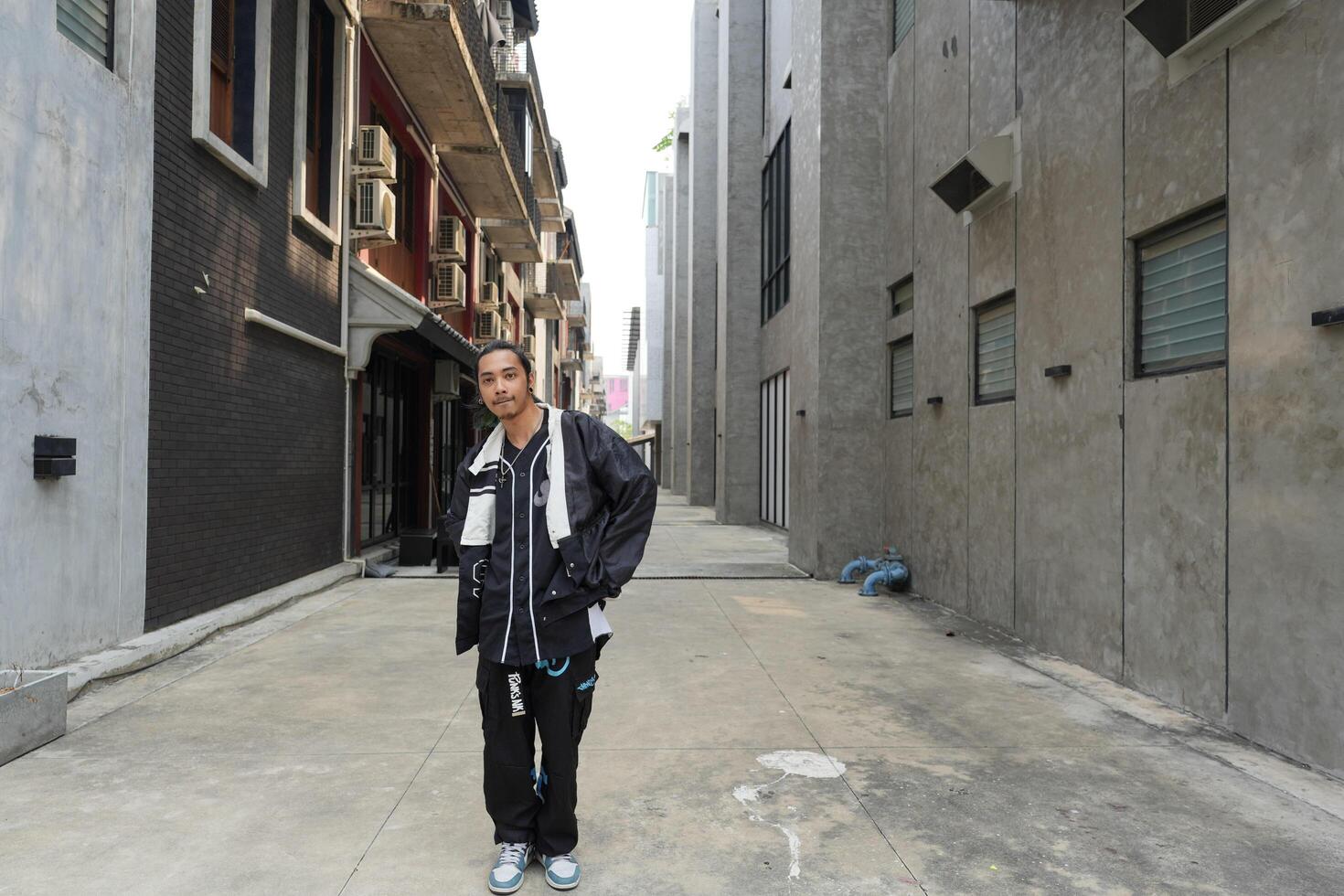 ASian man is dancing in hip hop style at outdoor space. Professional solo dancer is performing in public area. photo