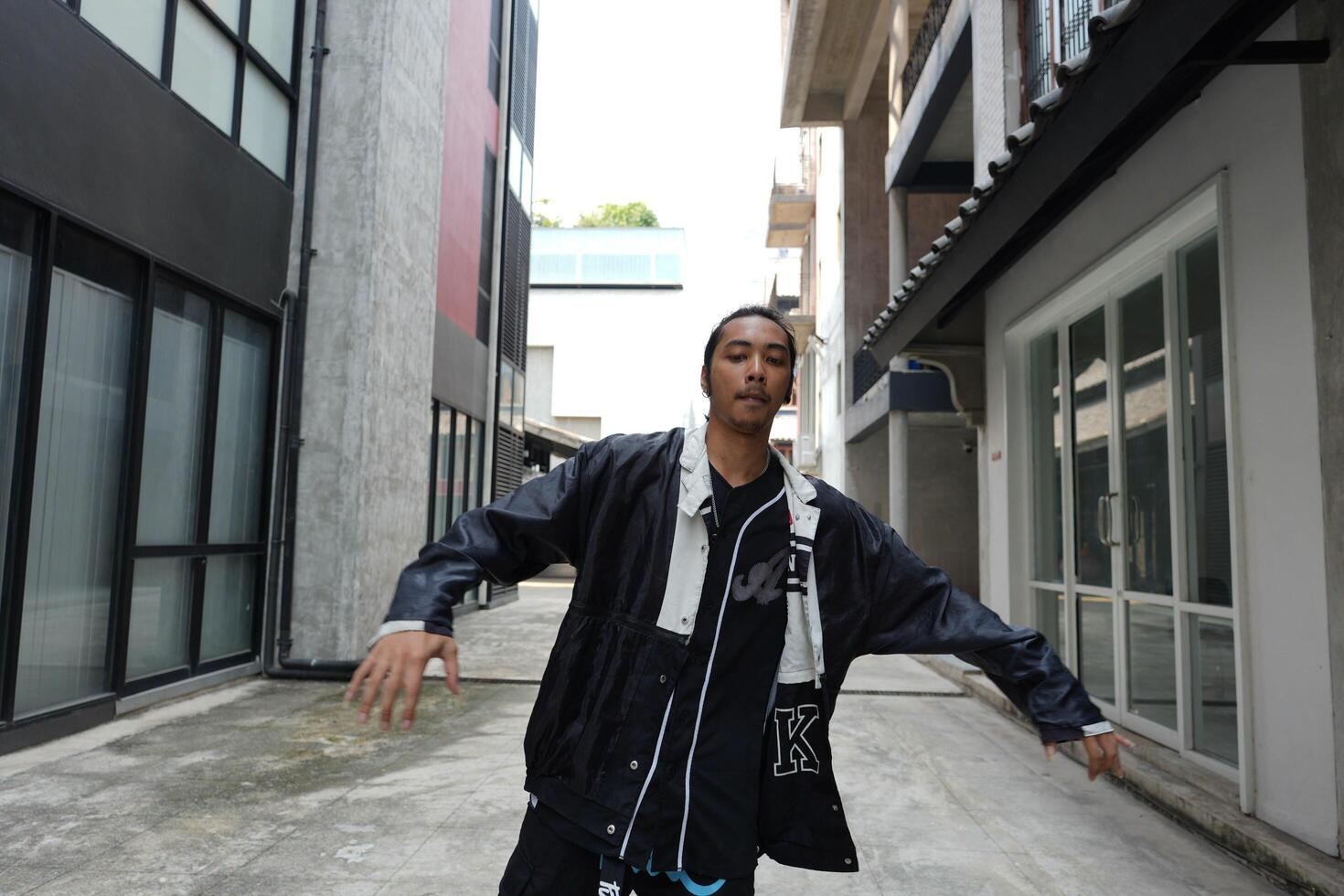 ASian man is dancing in hip hop style at outdoor space. Professional solo dancer is performing in public area. photo