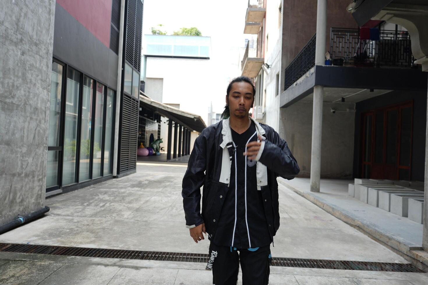 ASian man is dancing in hip hop style at outdoor space. Professional solo dancer is performing in public area. photo