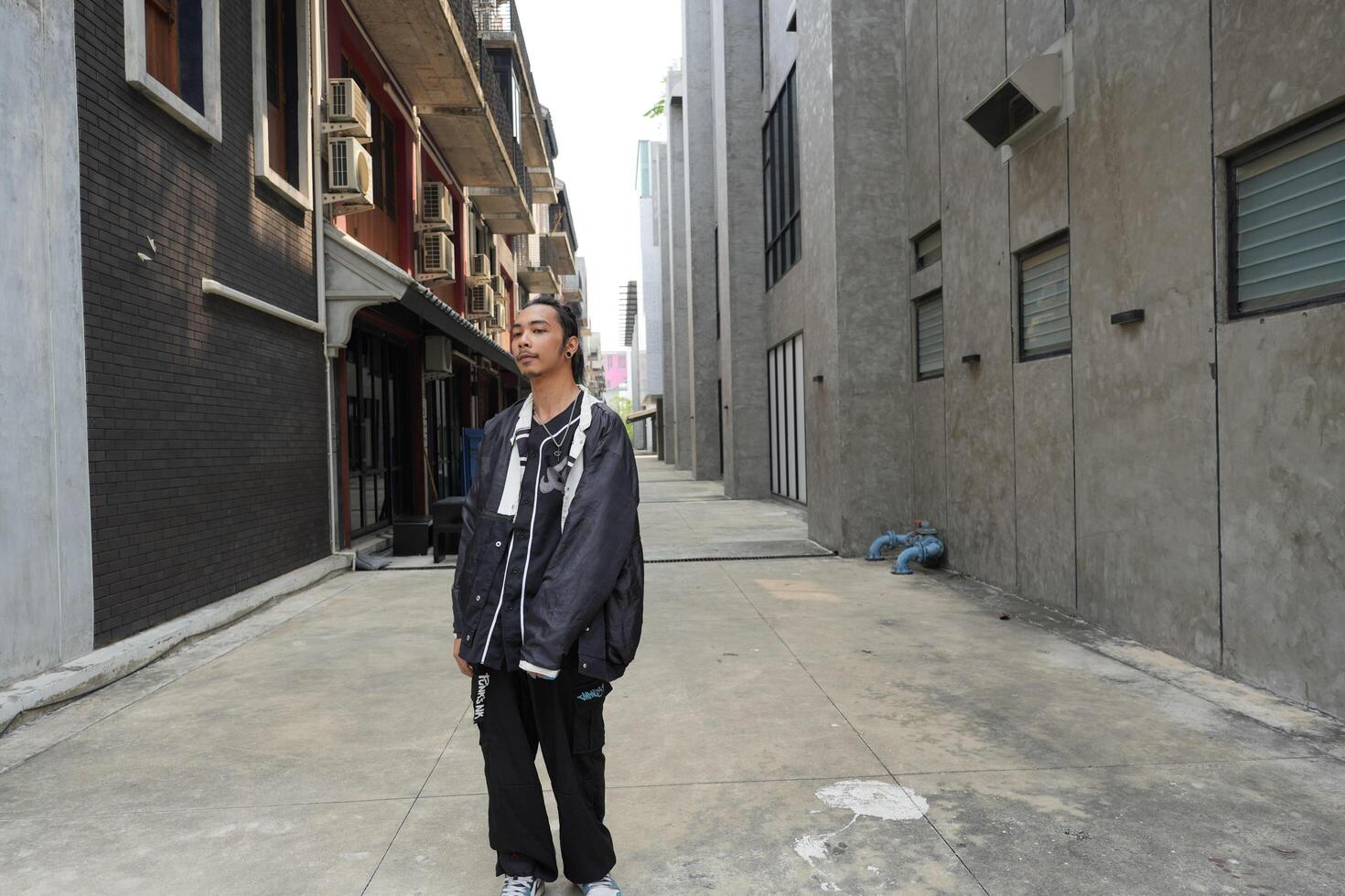 ASian man is dancing in hip hop style at outdoor space. Professional solo dancer is performing in public area. photo