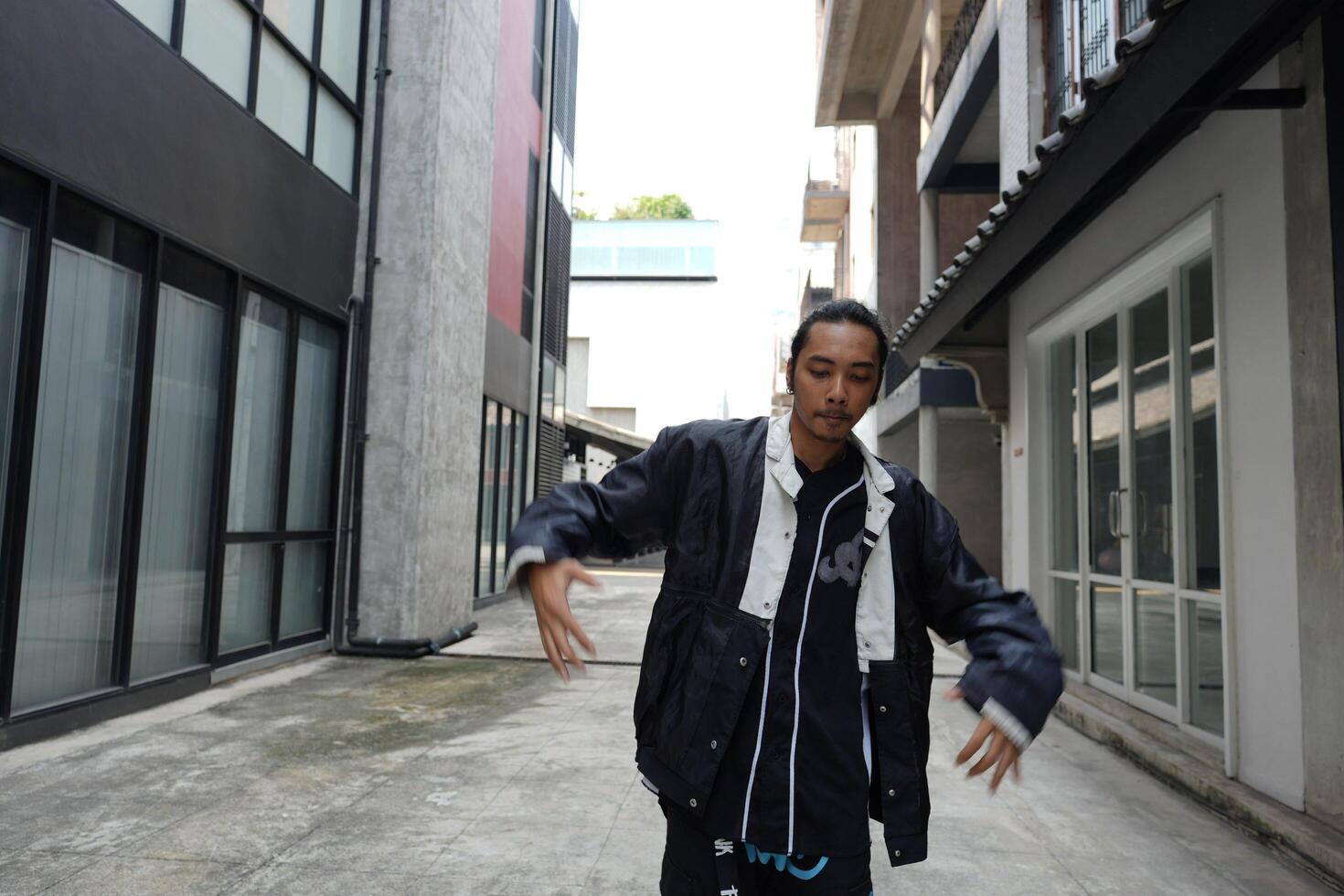 ASian man is dancing in hip hop style at outdoor space. Professional solo dancer is performing in public area. photo