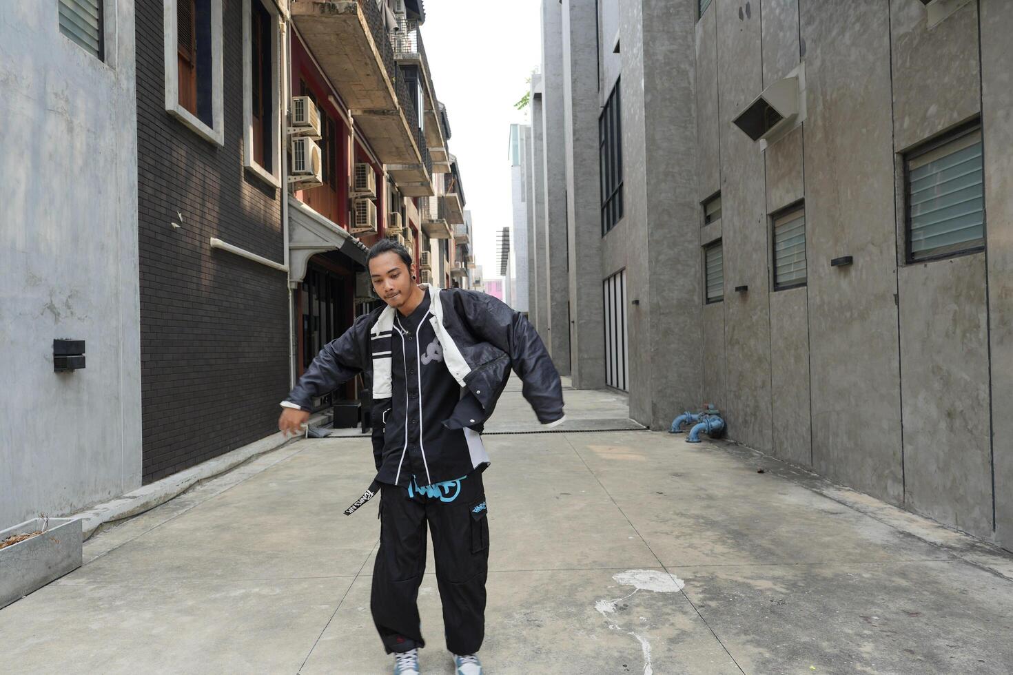 ASian man is dancing in hip hop style at outdoor space. Professional solo dancer is performing in public area. photo