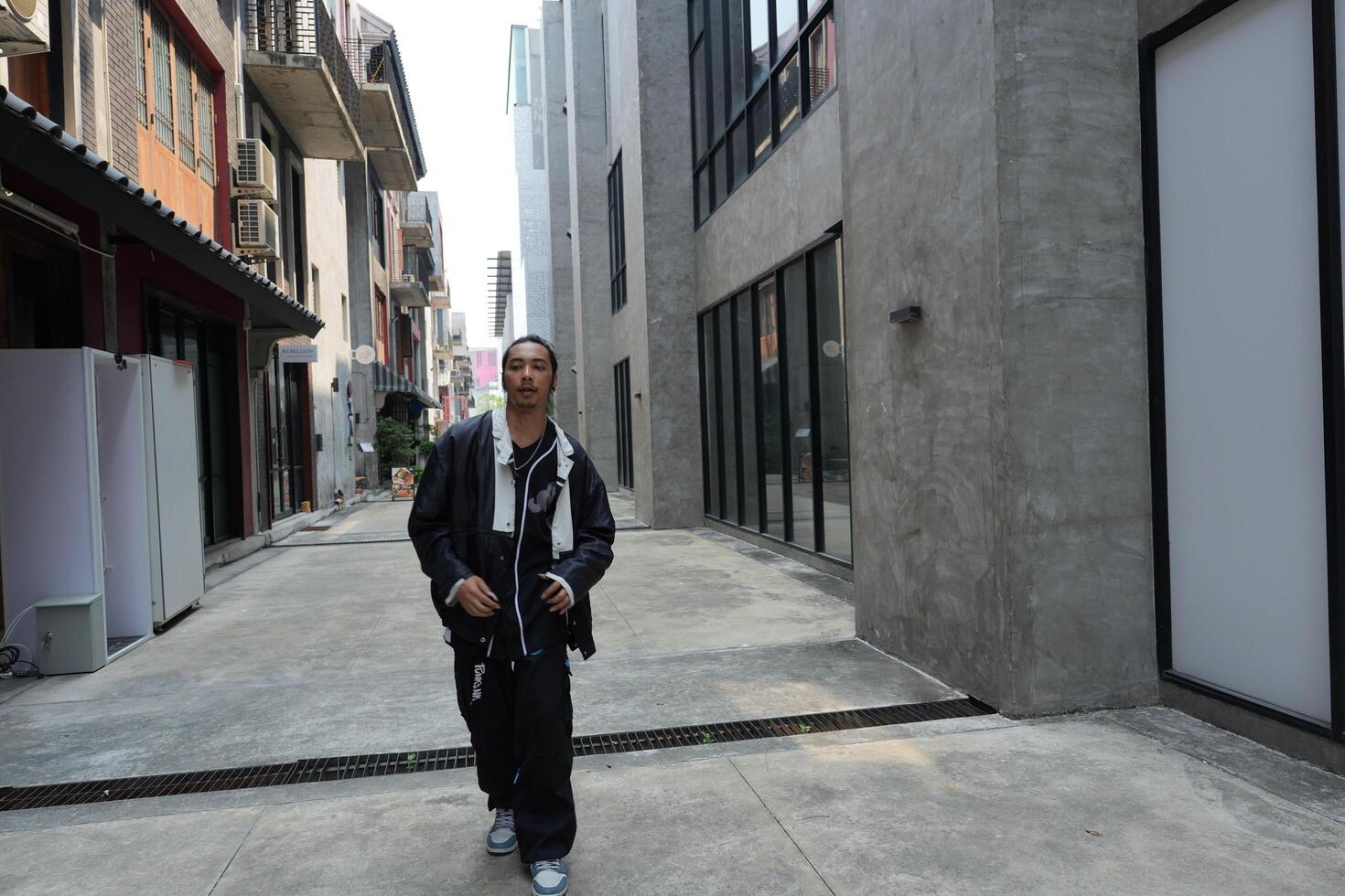 ASian man is dancing in hip hop style at outdoor space. Professional solo dancer is performing in public area. photo