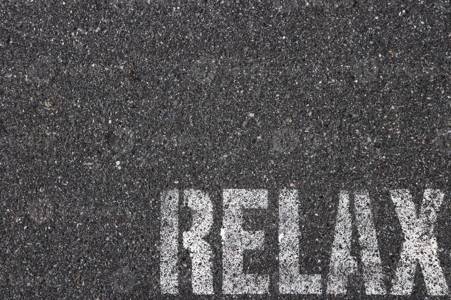 Road asphalt texture. Bitumen structure with painted relax word. photo