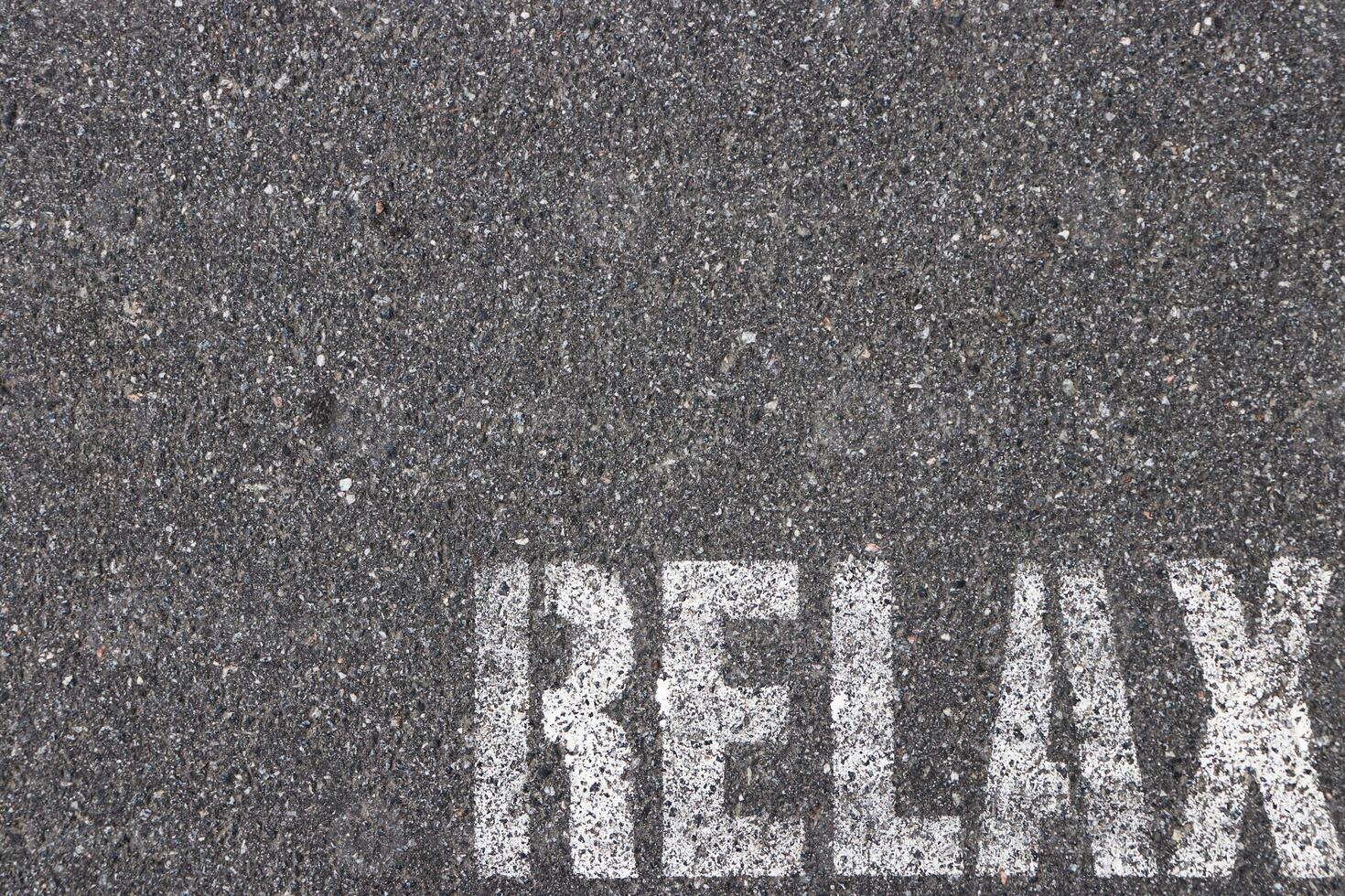 Road asphalt texture. Bitumen structure with painted relax word. photo