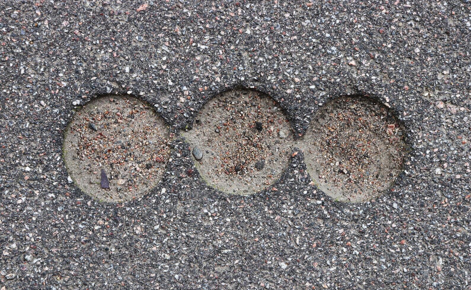 Road asphalt texture. Bitumen structure with 3 holes. photo