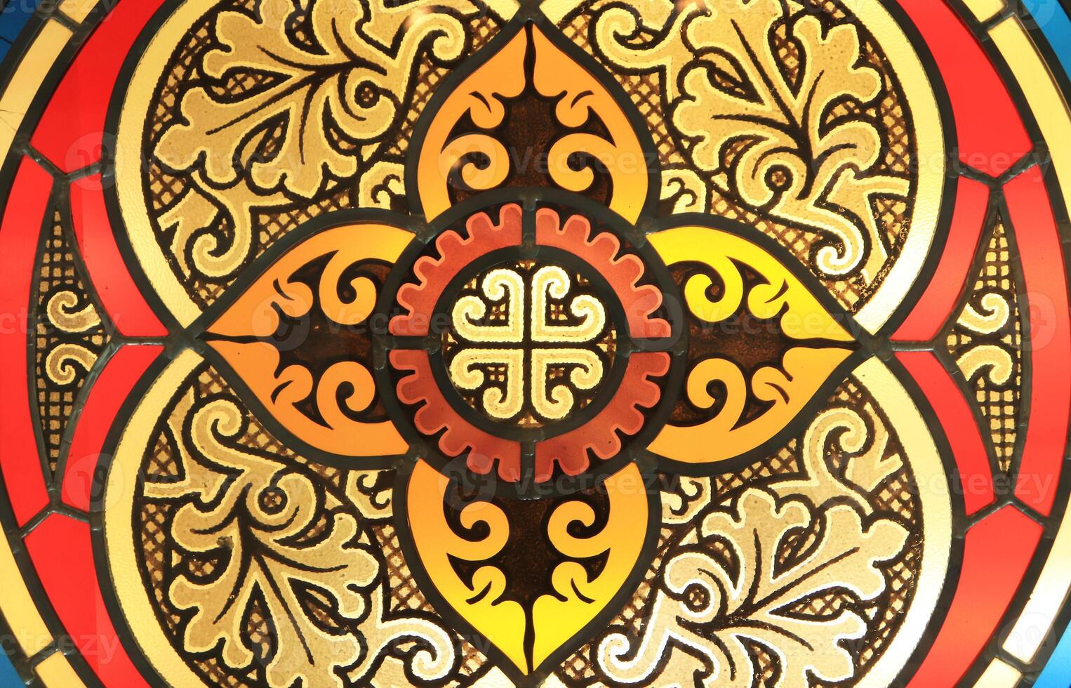 An antique cross is made of a stained glass window and is decorated with floral and geometric ornaments. photo