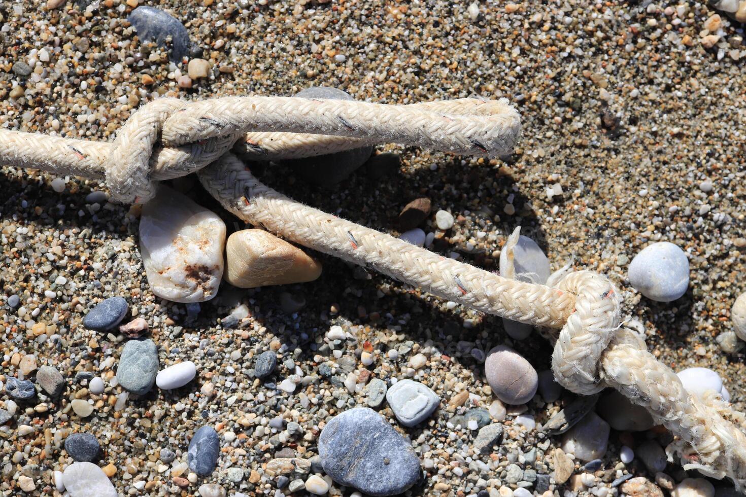 Rope with stone on sand beach photo