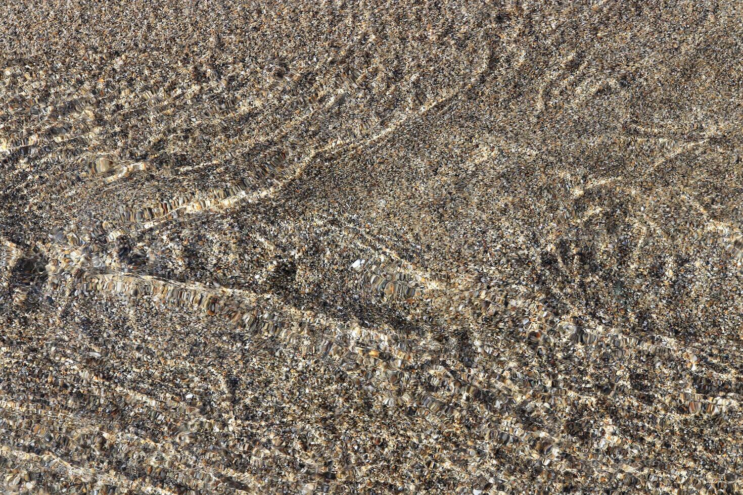 Aqua motion texture. Clear stream with sand on background. photo