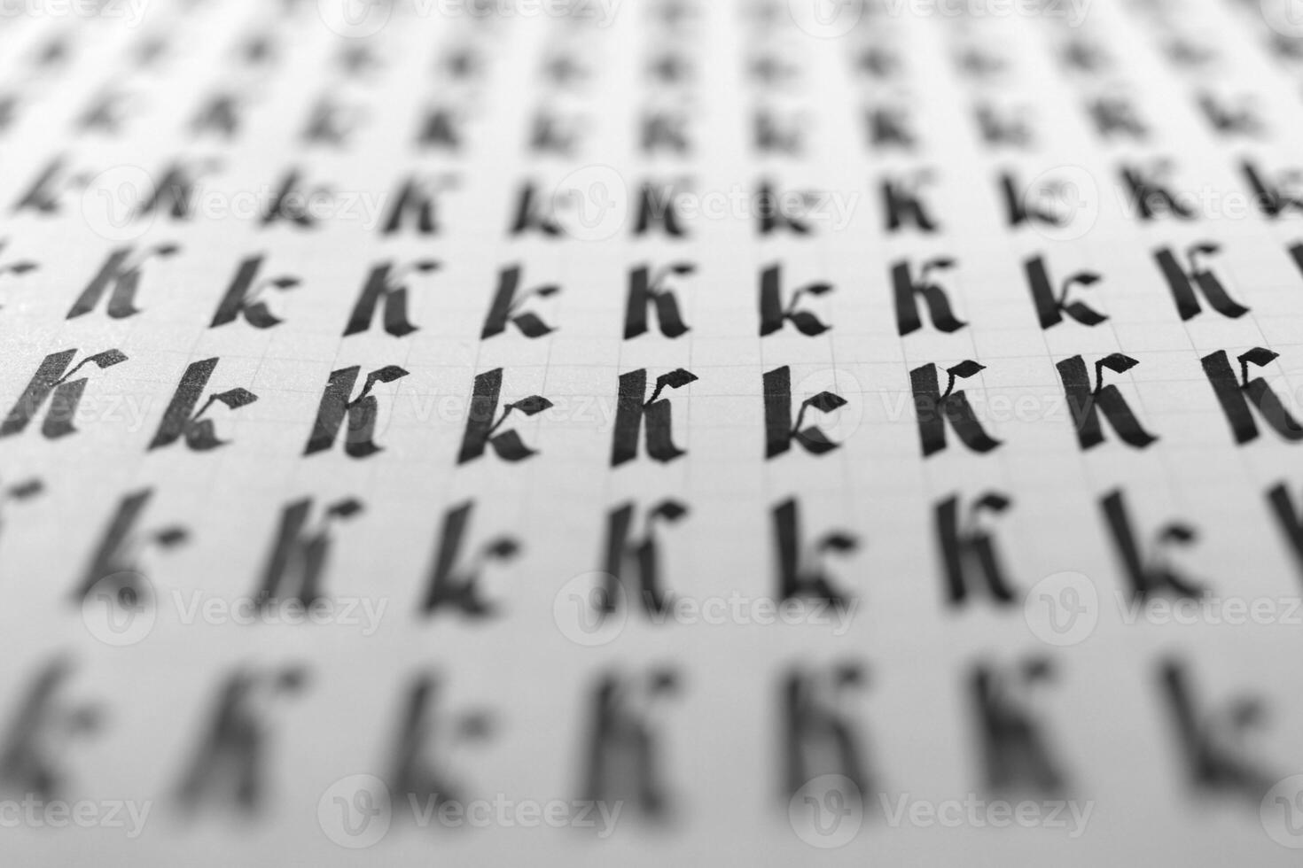 Handwriting black and white symbol filling pattern. Calligraphic letter K learning skills paper page. Calligraphy letters k background. Lettering practice writing worksheet. photo