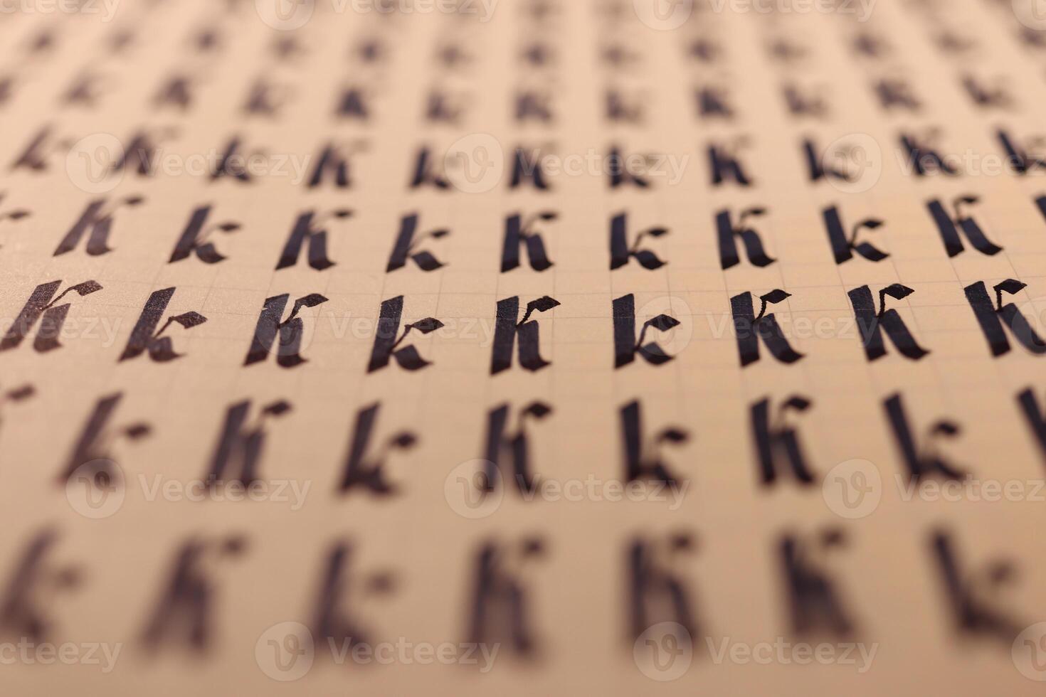 Handwriting symbol filling pattern. Calligraphic letter K learning skills paper page. Calligraphy letters k background. Lettering practice writing worksheet. photo