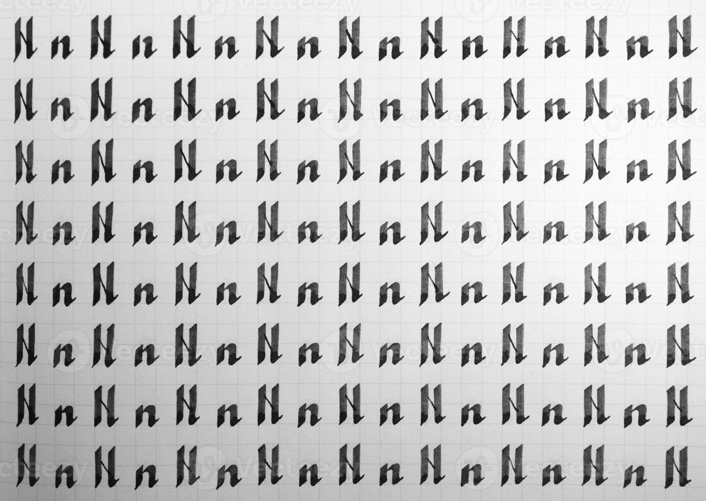 Handwriting black and white symbol filling pattern. Calligraphic letter N learning skills paper page. Calligraphy letters n background. Lettering practice writing worksheet. photo