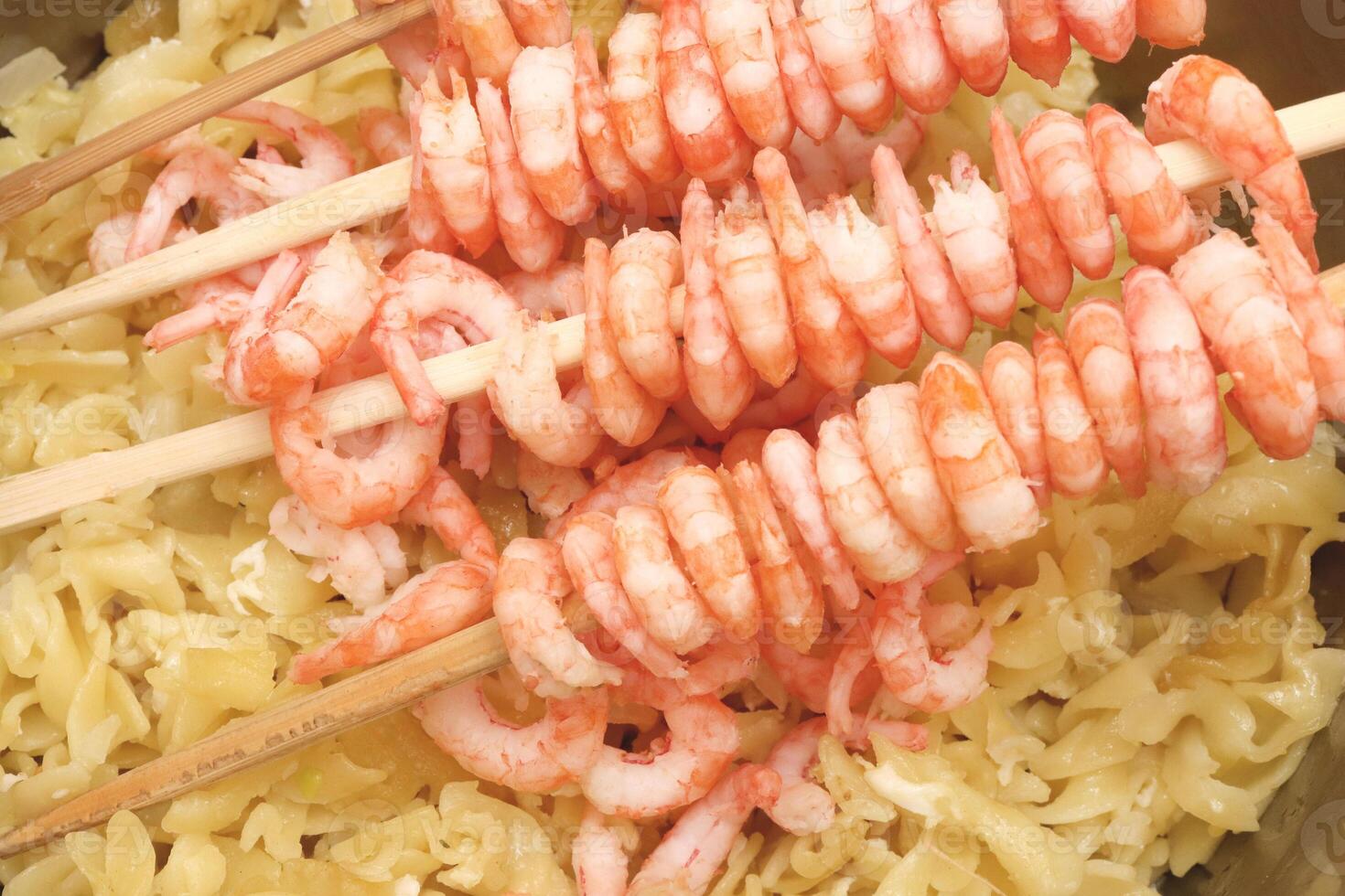 Rows of peeled boiled shrimp with macaroni. Many cooked prawns with pasta background. photo