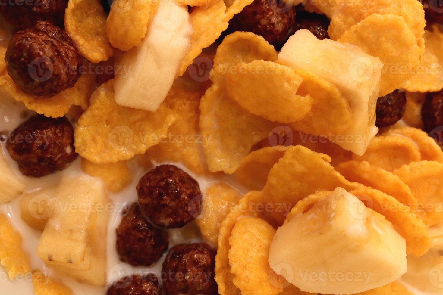 Cornflakes with chocolate balls sliced banana and milk. Filling background. Macro close-up. photo