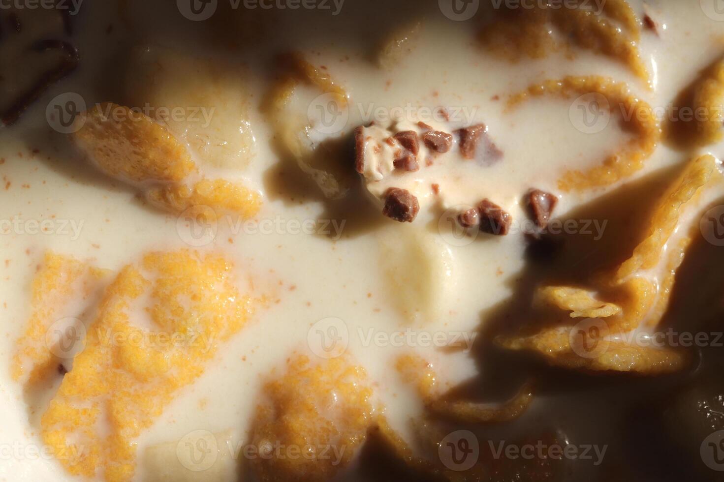 Cornflakes with chocolate sliced banana and milk in sun light. Filling background. Macro close-up. photo