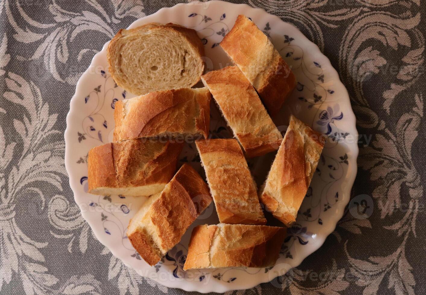 Chopped baguette pieces on a plate. Bread food on gray background. photo