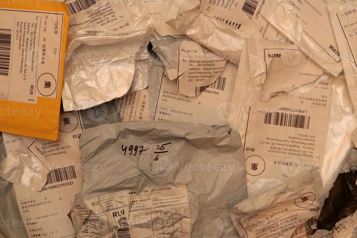 Many post packets and one yellow with labels filling background. photo