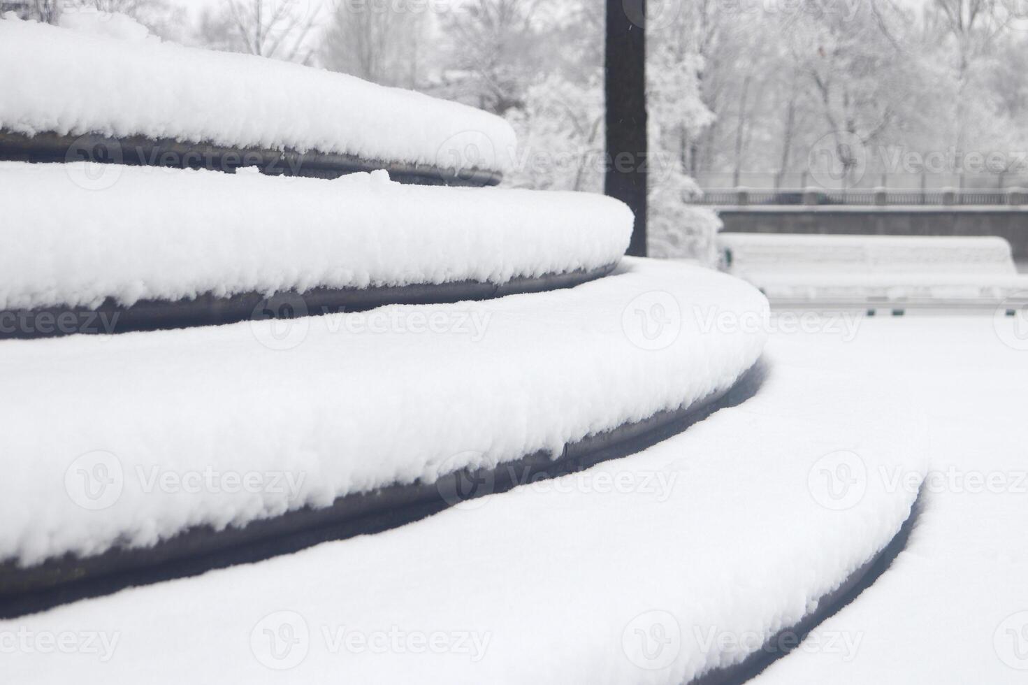 Pavilion under the flag round steps under a thick layer of snow. Landscape of winter park. photo