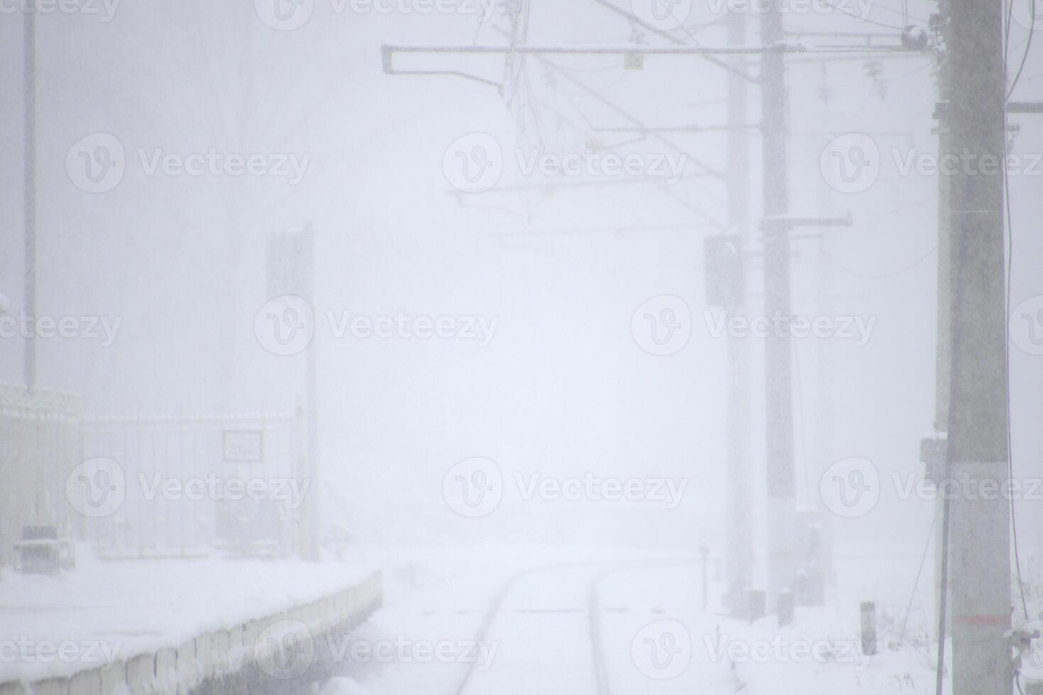 Snow-covered railway tracks with a railway station going into the distance. Winter background. photo