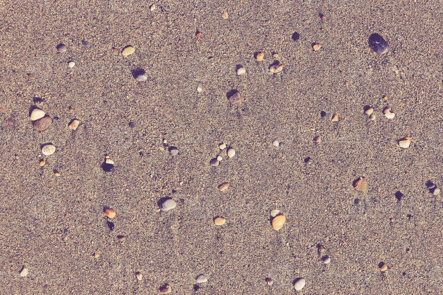 Different stones with stains on the wet sand. Rare pebble background. Beach beauty backdrop. photo