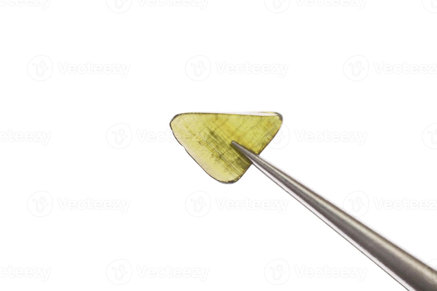 Tourmaline jewel stone texture in tweezers on white light isolated background. Macro closeup. photo