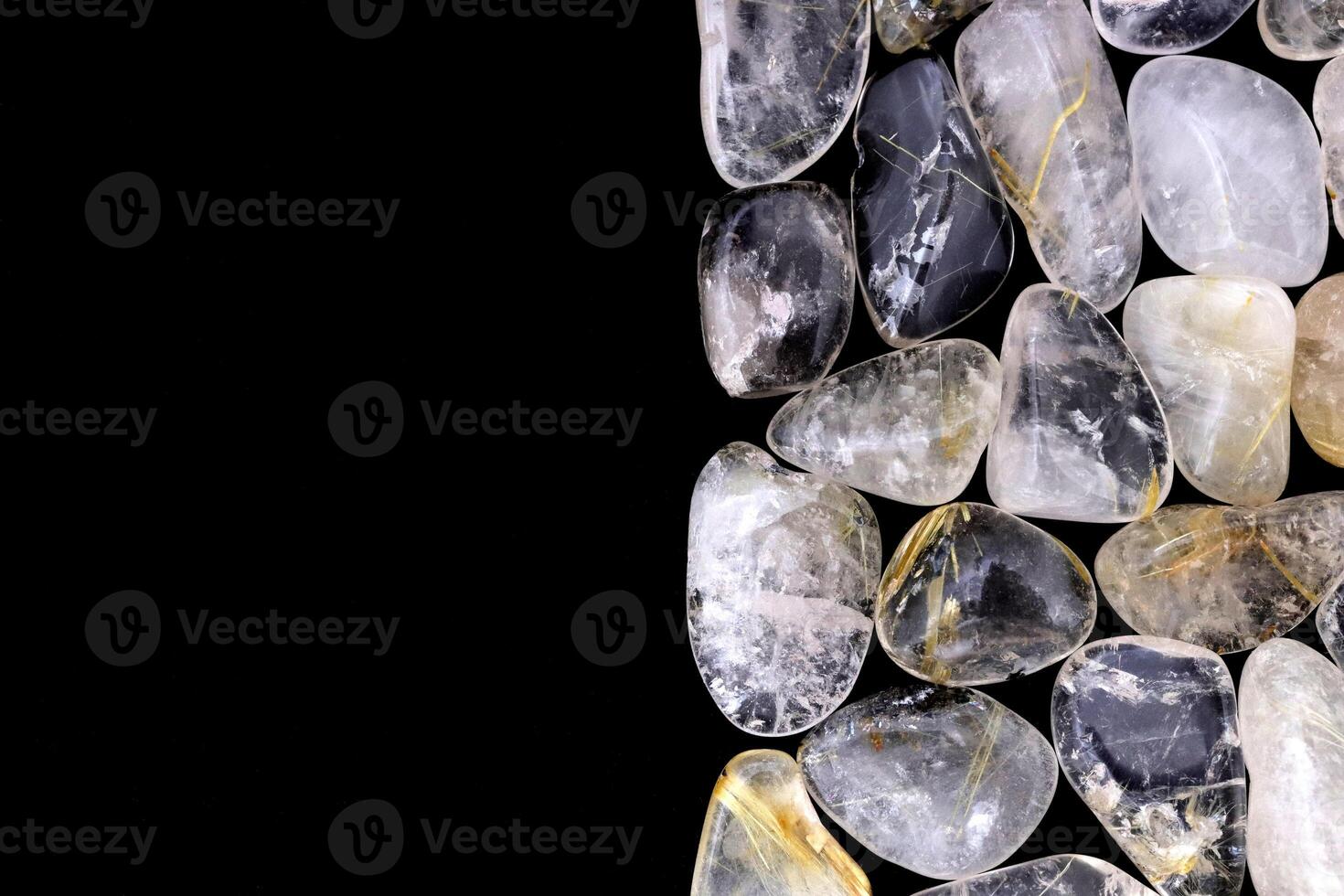 Rutilated quartz heap jewel stones texture on half black background. Place for text. photo