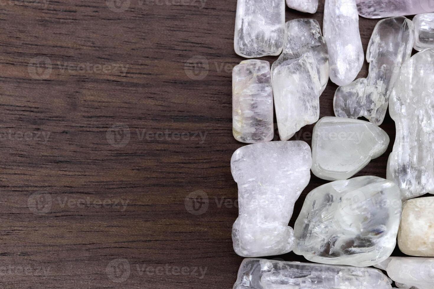 Clear kunzite heap jewel stones texture on half brown varnished wood background. Place for text. photo