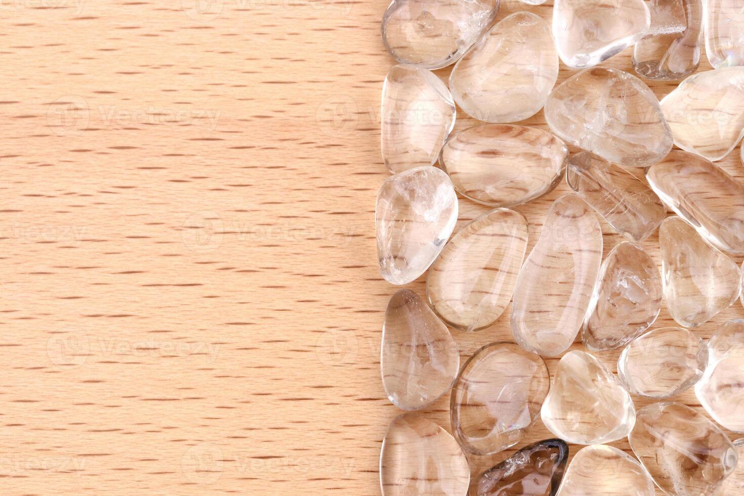 Smoky quartz heap jewel stones texture on half light varnished wood background. Place for text. photo