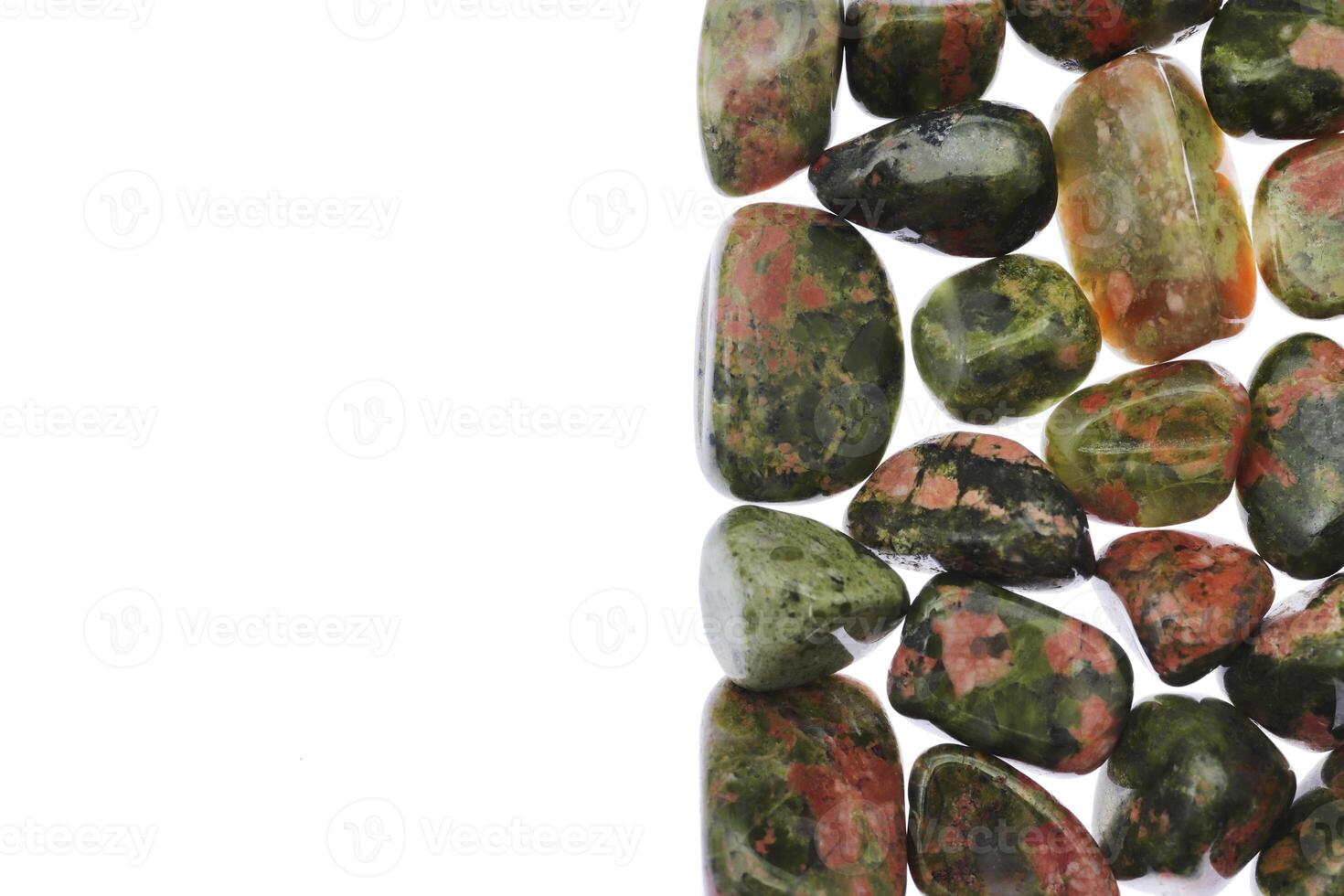 Unakite heap jewel stones texture on half white light isolated background. Place for text. photo
