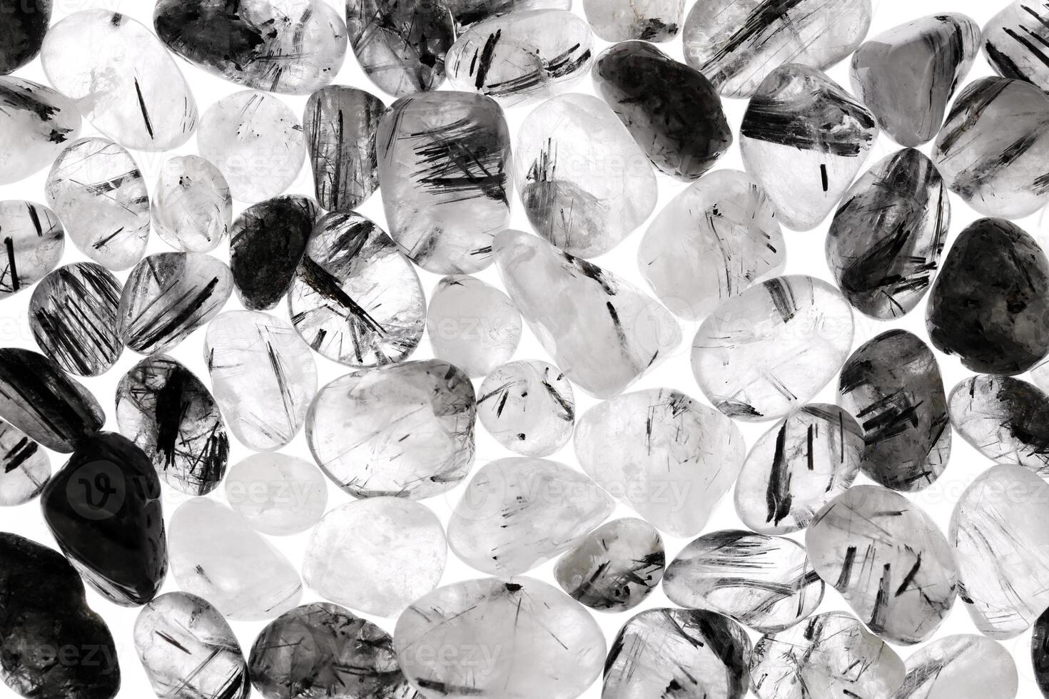 Tourmalinated quartz heap jewel stones texture on white light background photo