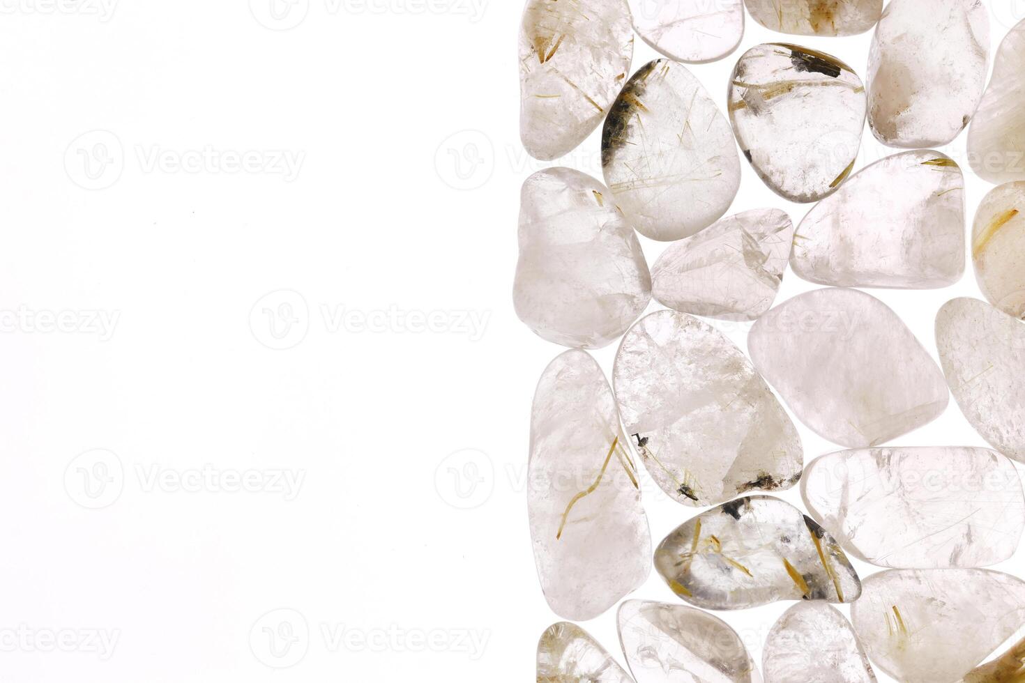 Rutilated quartz heap jewel stones texture on half white light isolated background. Place for text. photo