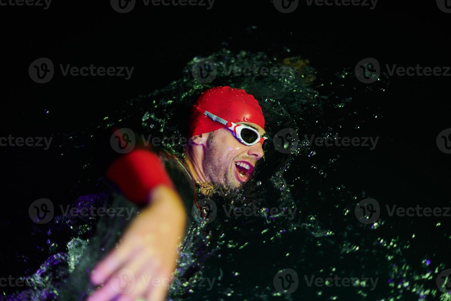 Authentic triathlete swimmer having a break during hard training on night neon gel light photo