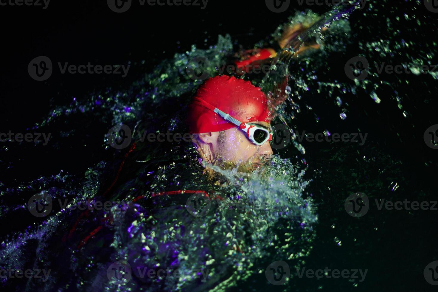Authentic triathlete swimmer having a break during hard training on night neon gel light photo