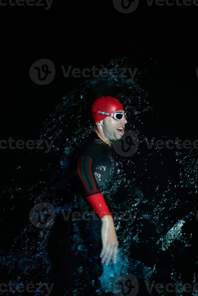 Authentic triathlete swimmer having a break during hard training on night neon gel light photo
