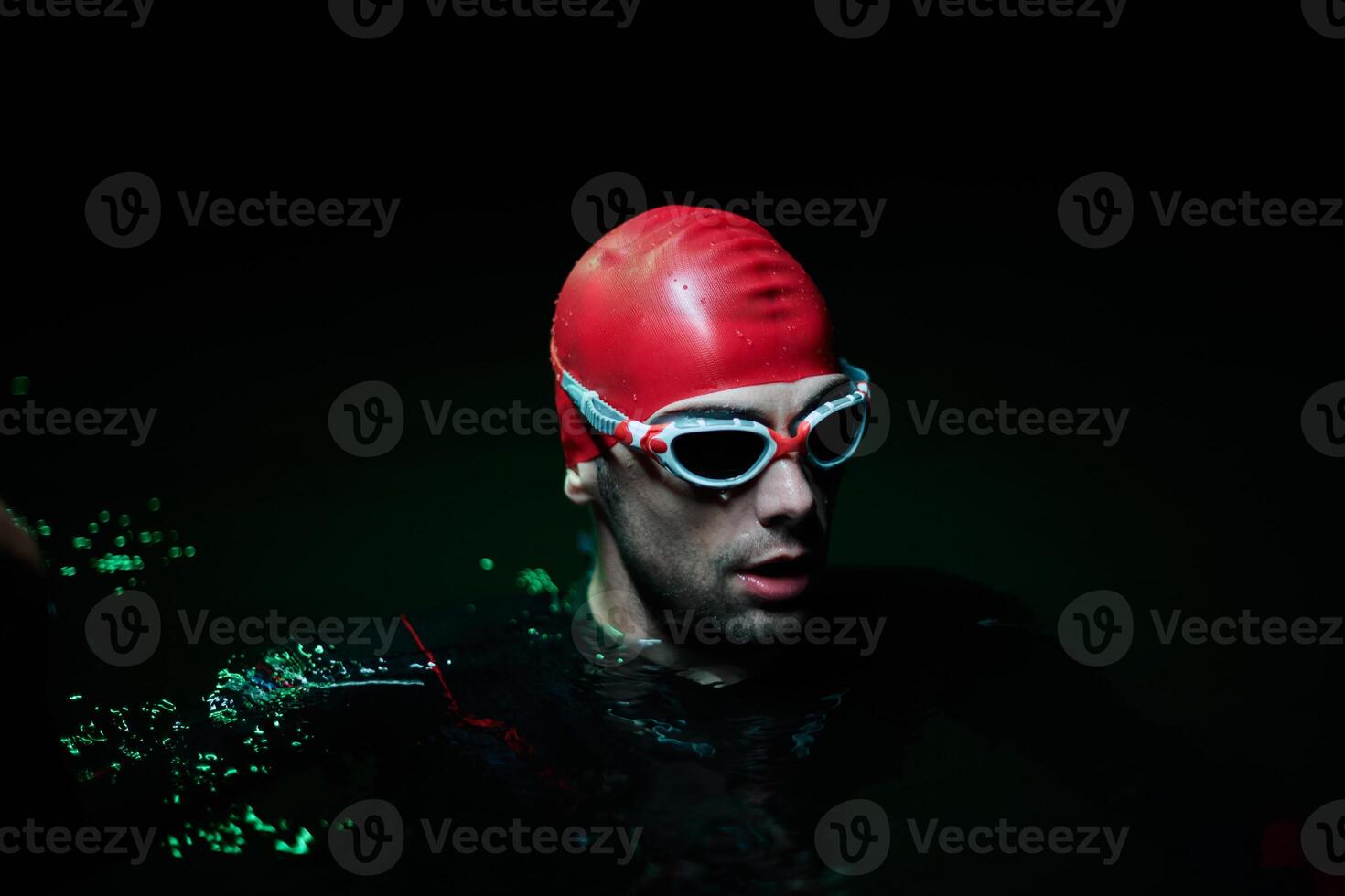Authentic triathlete swimmer having a break during hard training on night neon gel light photo