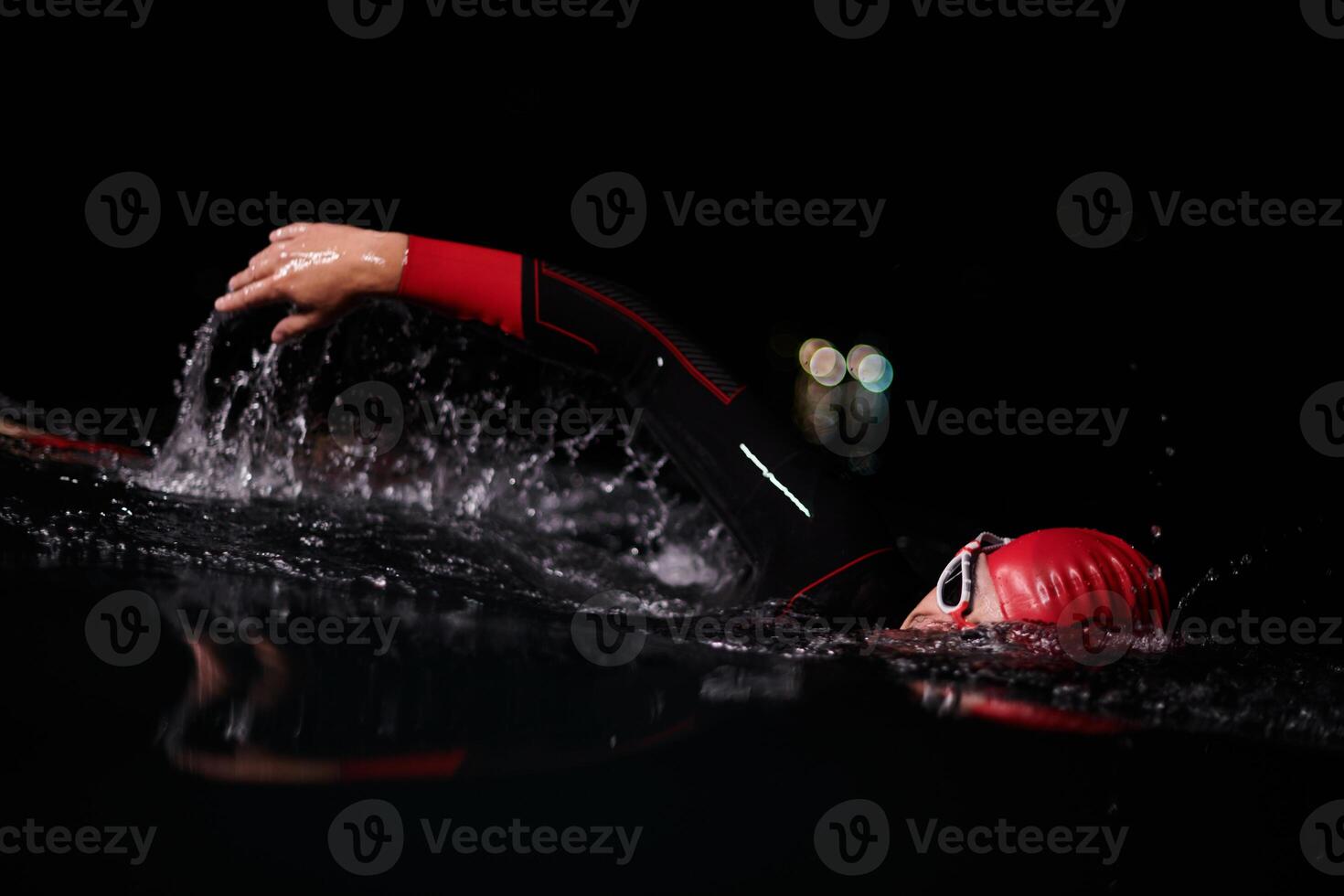 A determined professional triathlete undergoes rigorous night time training in cold waters, showcasing dedication and resilience in preparation for an upcoming triathlon swim competition photo