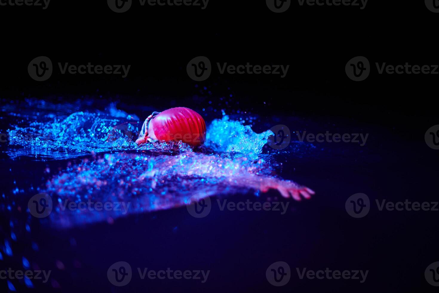 Authentic triathlete swimmer having a break during hard training on night neon gel light photo