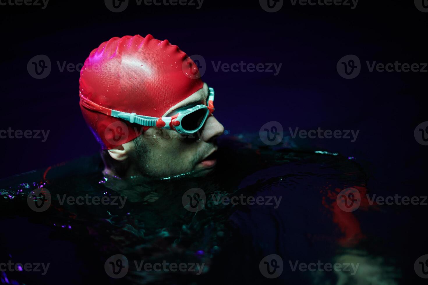 Authentic triathlete swimmer having a break during hard training on night neon gel light photo
