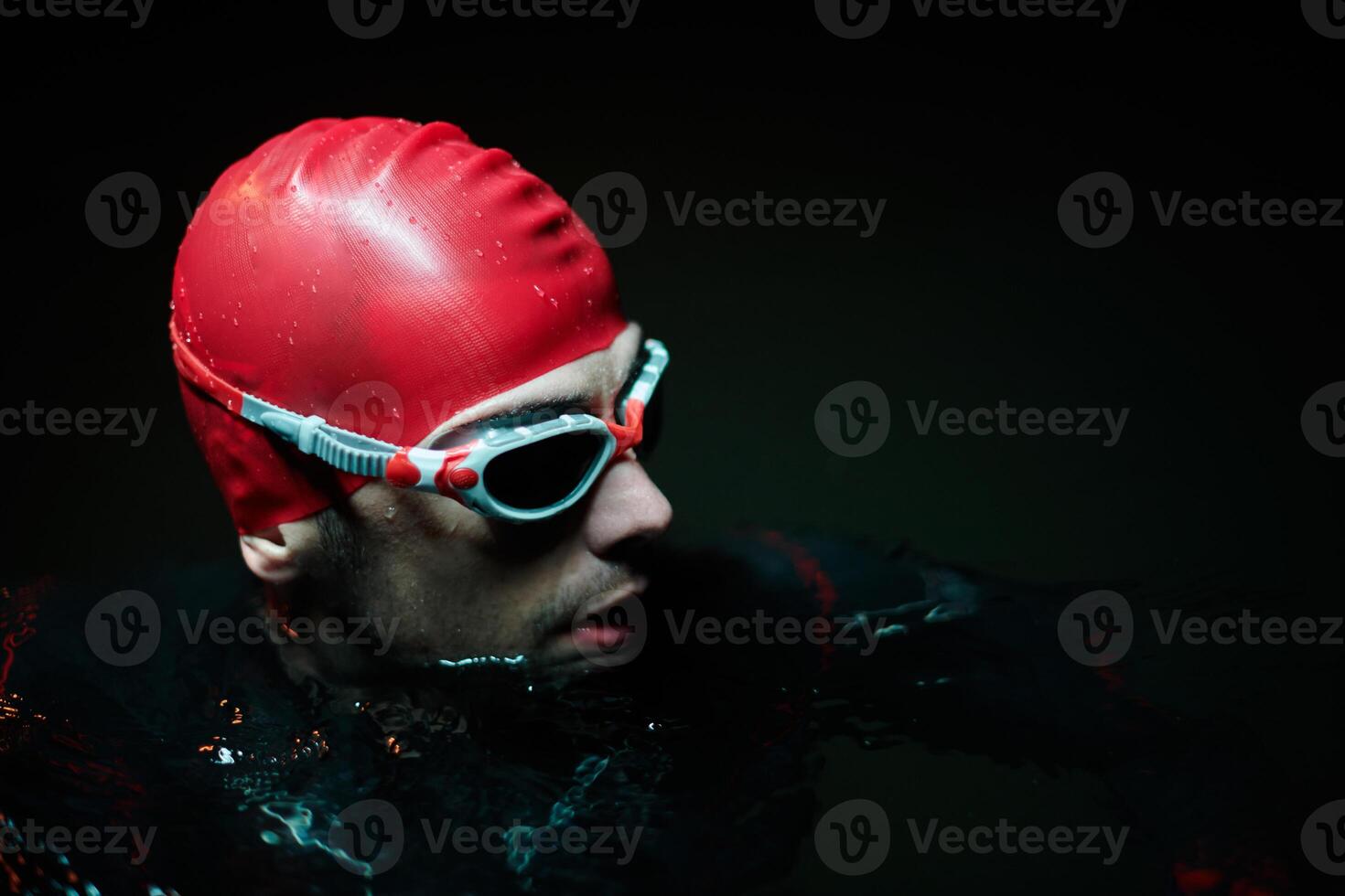Authentic triathlete swimmer having a break during hard training on night neon gel light photo