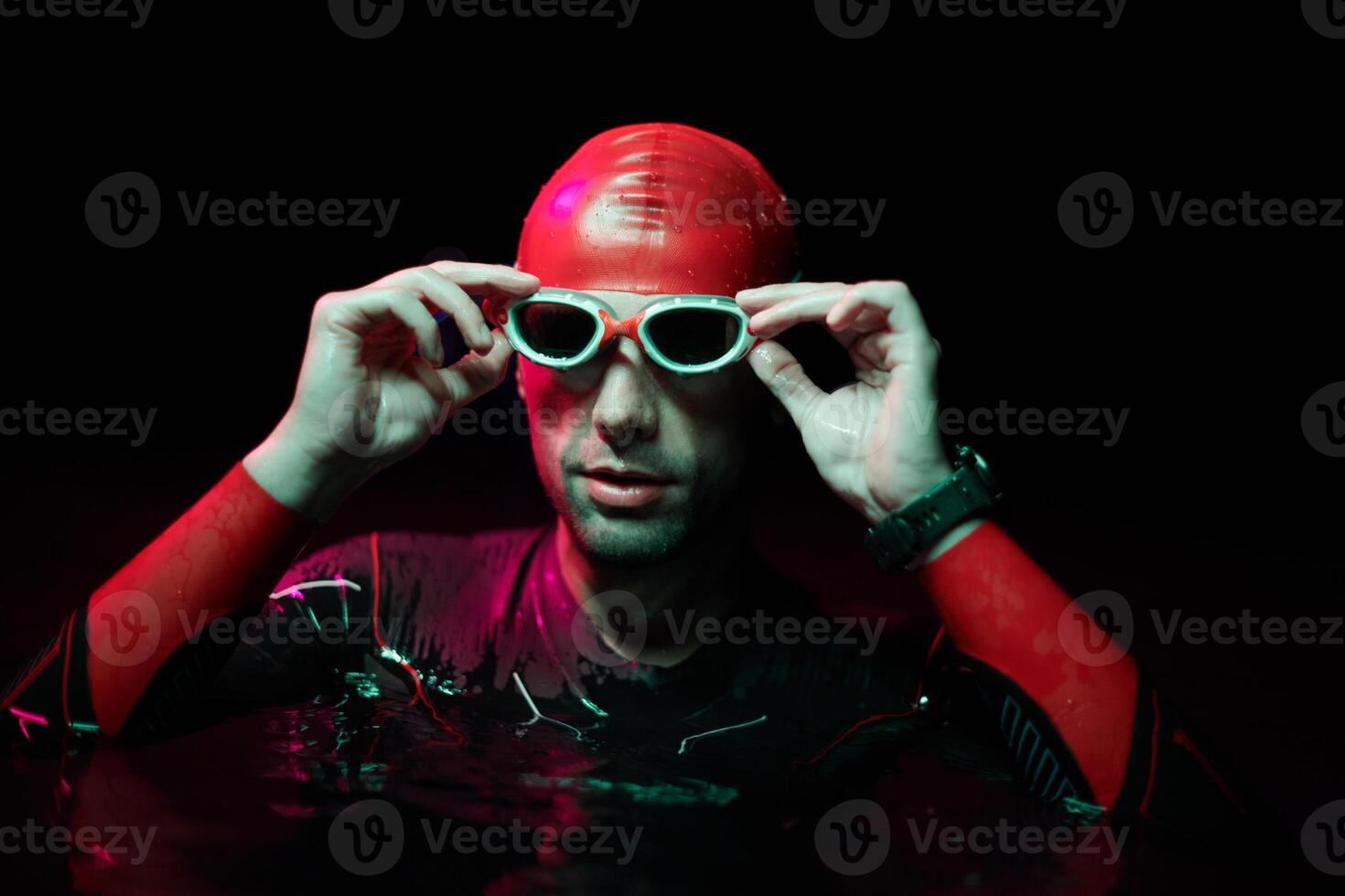 Authentic triathlete swimmer having a break during hard training on night neon gel light photo