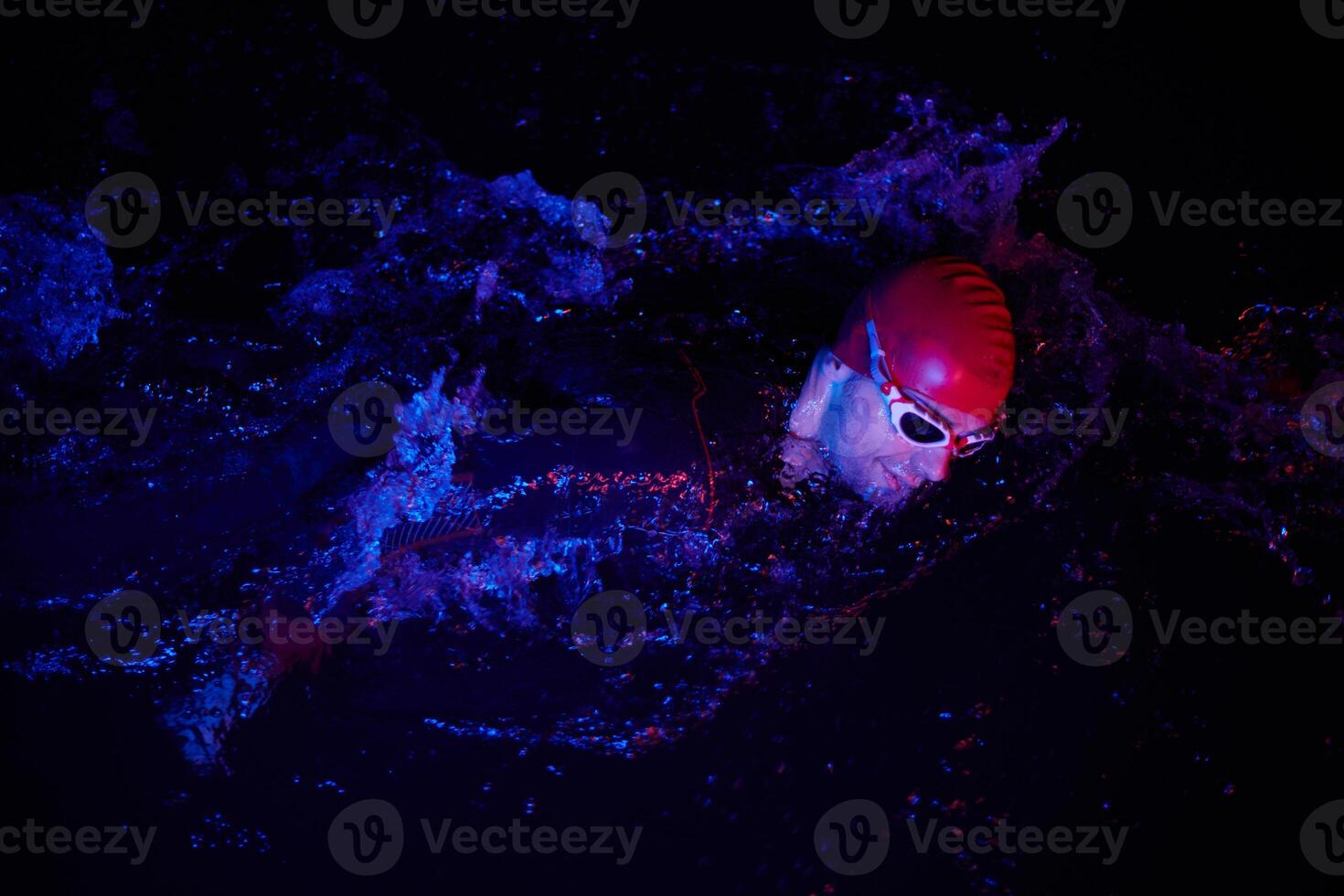 Authentic triathlete swimmer having a break during hard training on night neon gel light photo