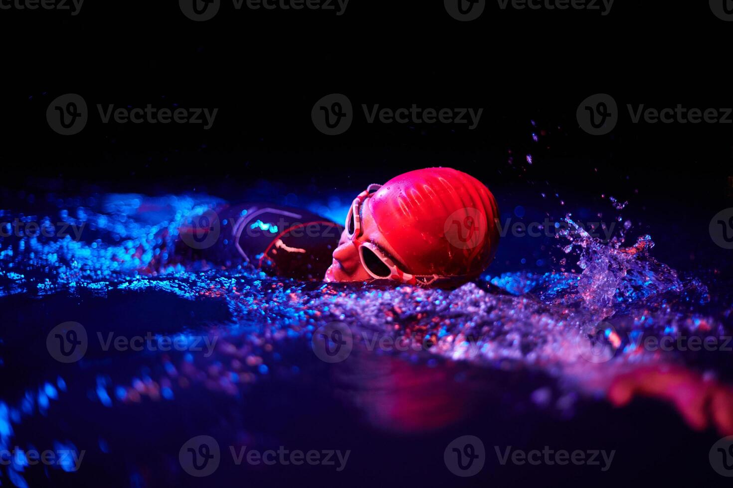 Authentic triathlete swimmer having a break during hard training on night neon gel light photo